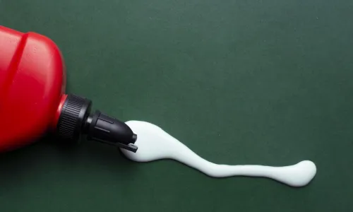 glue oozing out of a red bottle onto a green table