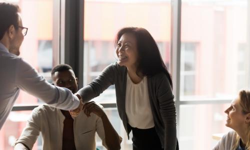 business manager recognizes employee during meeting by shaking hands