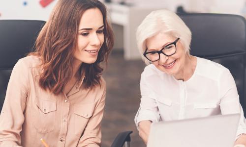 young female employee works in harmony with older baby boomer employee at the office