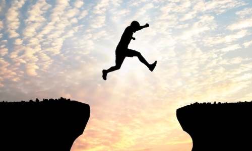 man jumping gap in mountains