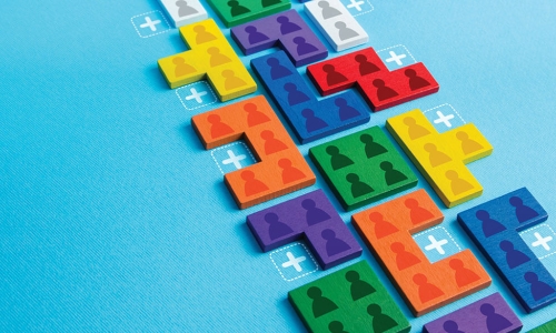 Stack of colorful Tetris puzzle pieces representing people and teams with empty plus-sign spots to fill in