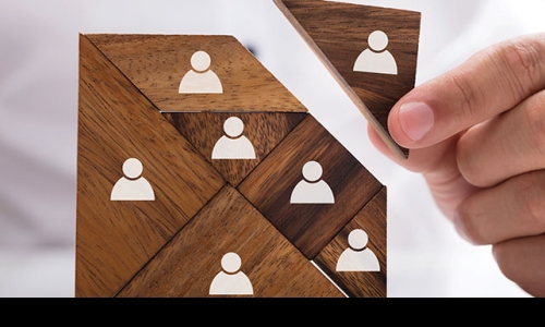 hand placing final wooden puzzle piece with people icon on it