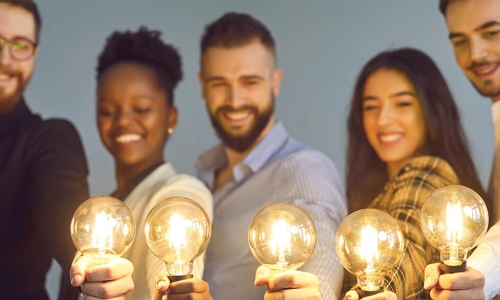 Group of young businesspeople holding up glowing lightbulbs
