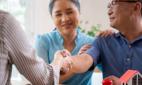 happy couple shakes hands with loan officer after securing a mortgage for new home