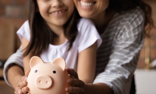 happy mother and young daughter holding piggy bank