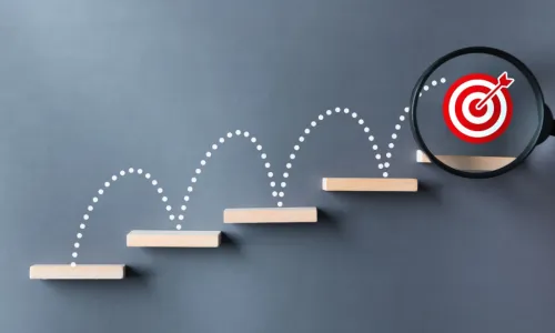 stairs dart and dartboard targets magnifying glass with hand on gray background