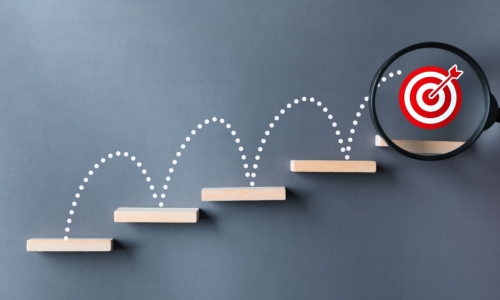 stairs dart and dartboard targets magnifying glass with hand on gray background