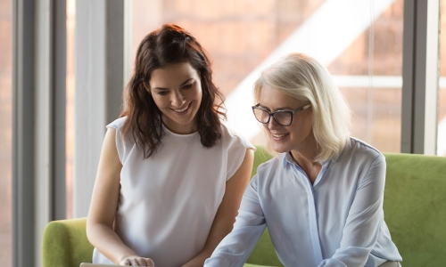 two women talking over a computer screen