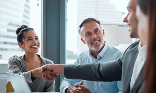 individuals shaking hands over laptop