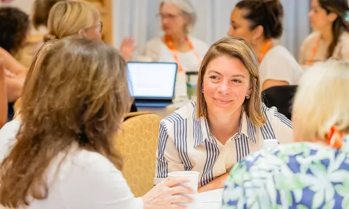 women engaging in conversation around a table at CUES Symposium conference
