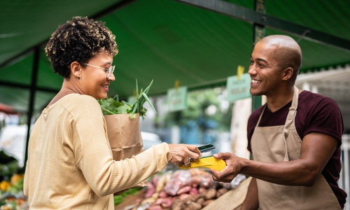 woman making a purchase at farmers market stand