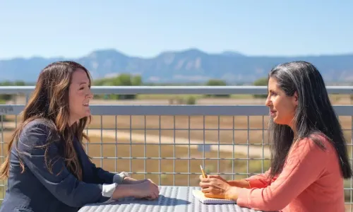 2 women talking at outdoor table