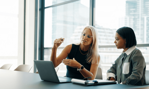 2 women looking at a laptop on a table