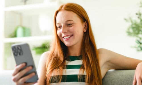 woman smiling looking at her smartphone